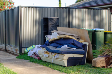 household waste or hard rubbish of a discarded sofa, rugs and assorted debris piled at front yard...