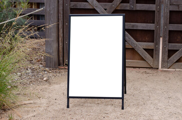 Empty outdoor advertising stand against a rustic wooden background. Blank white mockup template of...