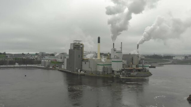 Aerial shot of the Irving Pulp and Paper factory shooting toxic smoke into the air on a cloudy day near the reversing falls.
