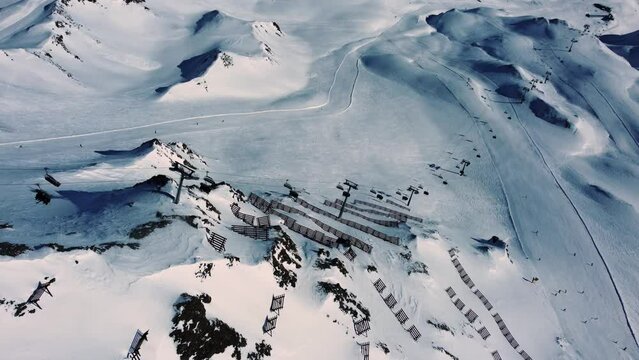 Above long chair lift going up steep mountain with avalanche fences, Alps
