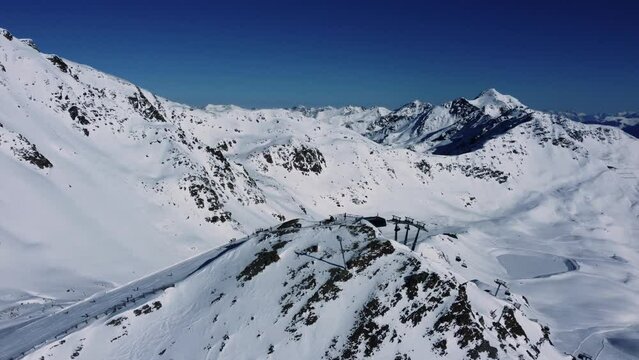 Mountain chair lift in during winter season in Alps on high peak, aerial