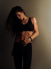 Sport muscular woman relaxing after training in black sport bra looking on strong abs on dark shadow studio background. Sexy body. Sporty art toned - 769295753