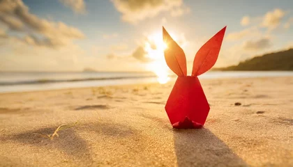 Fotobehang creative easter concept photo of red paper bunny on the sand on the beach at sunset concept of easter celebrations in tropical countries © Ryan