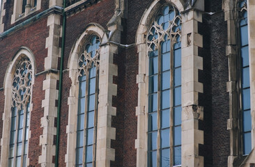 Three old pointed openwork gothic windows with stained glass on facade of the building. Baroque and Gothic architecture. Church of St. Olga and Elizabeth. Lviv, Ukraine.
