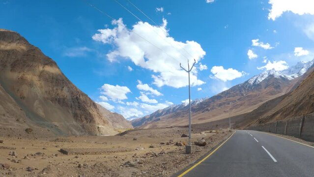 4K POV shot of a vehicle driving in the Himalayan roads during a cloudy day with blue sky on the way to Padum in Zanskar Valley, Ladakh, India. Beautiful scenic view of roads in Ladakh. Road trip.