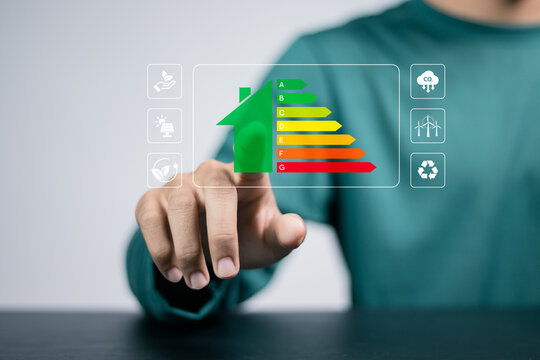 Energy efficiency concept. Person touching energy efficiency rating icon on virtual screen for energy efficient house building rate label audit.