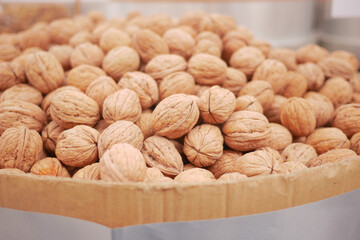 A scoop of walnuts, a superfood, rests on a stack of nuts seeds