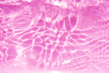 Pink water bubbles on the surface ripple. Defocus blurred transparent pink colored clear calm water surface texture with splash and bubbles. Water waves with shining pattern texture background
