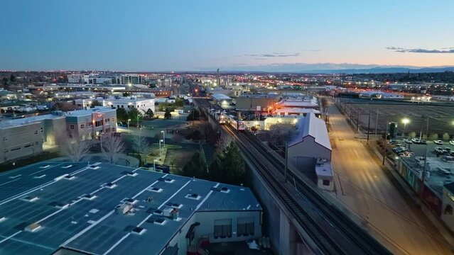 Public transportation trains pass each other on rail tracks at dusk during evening commute, aerial overview