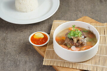 Bowl of meat soup on a wooden table