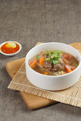 Bowl of meat soup on a wooden table