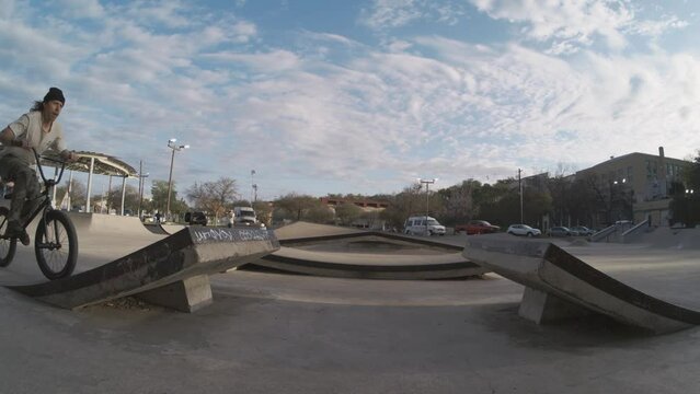 Biker doing huge air bar spin off kicker ramp at skatepark in 800fps extreme slow motion, sunrise bmx in 4k
