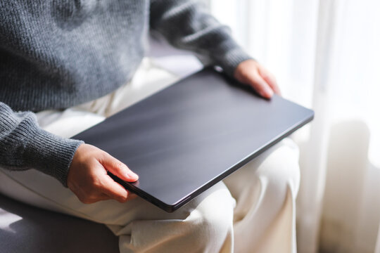 Closeup image of a woman holding laptop computer at home