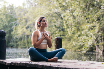 woman meditating in nature near a lake