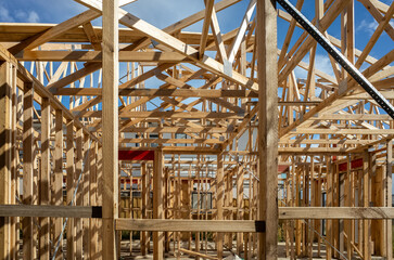 Wooden beams, the skeletal framework of a house under construction, the beginnings of residential architecture and the potential of a future home. Concept of housing market, real estate development.