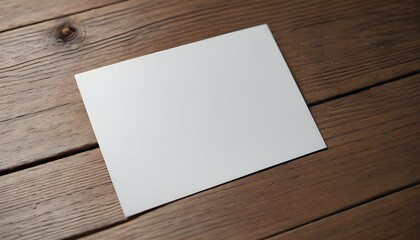 An overhead view of a blank white paper card placed on a wooden surface, slightly tilted to the side, awaiting heartfelt words to be penned. - obrazy, fototapety, plakaty