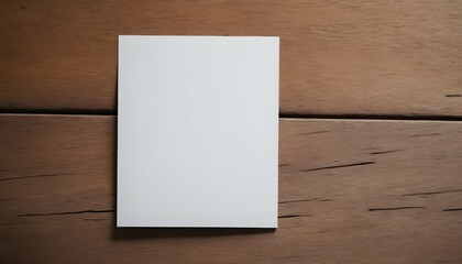 An overhead view of a blank white paper card placed on a wooden surface, slightly tilted to the side, awaiting heartfelt words to be penned.