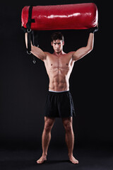Portrait, punching bag and man with training, exercise or fitness on dark studio background. Face,...