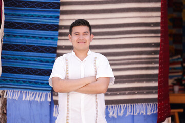 Portrait of young Mexican man smiling in typical Mexican clothing, looking at the camera with his...