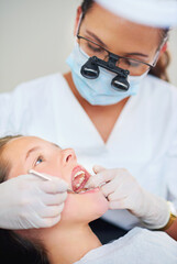 Girl, child and tool for inspection at dentist for healthcare with dental mirror, consultation and checkup for oral health. Magnifying glass, kid and glove hand for teeth cleaning and medical care