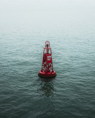 A red buoy in the ocean in the mist