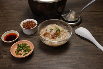 Asian thick rice porridge bubur chicken beef meat fish prawn rustic silver pot ladle serving in...