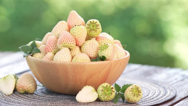 Pink snow strawberry on wooden Table, White and Pink snow Strawberries with slices on  green bokeh background.