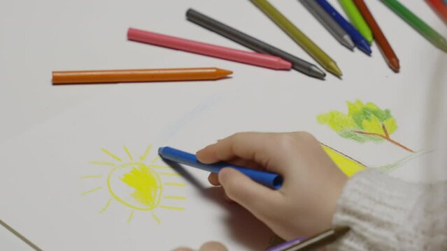 Close-up of hands of unidentified little child  drawing house .child coloring, colored pencils, preschool drawing