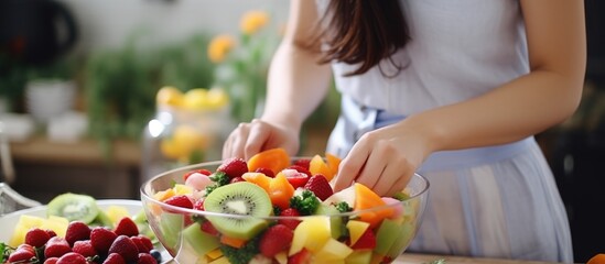 A woman is skillfully assembling a fruit salad in a bowl, combining natural foods and plantbased...
