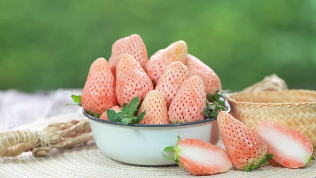 Pink snow strawberry on wooden Table, White and Pink snow Strawberries with slices on  green bokeh background.