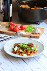 rice with meat and vegetables in a frying pan on a wooden background