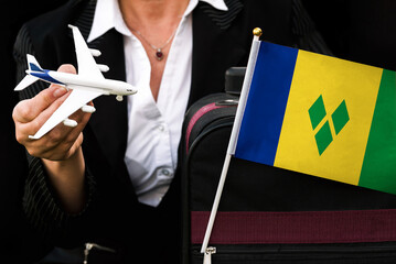 business woman holds toy plane travel bag and flag of Saint Vincent and the Grenadines
