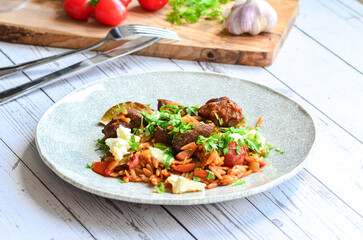 rice with meat and vegetables in a frying pan on a wooden background