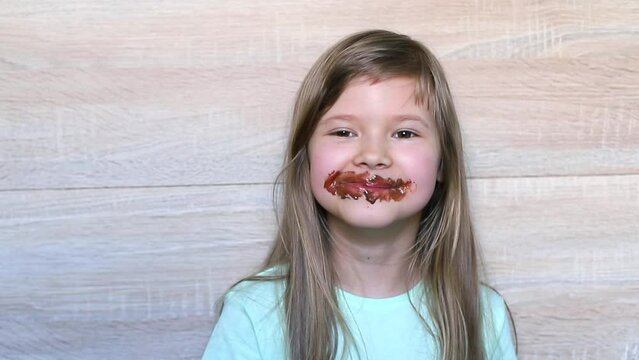 Laughing little girl eating chocolate dirty face
