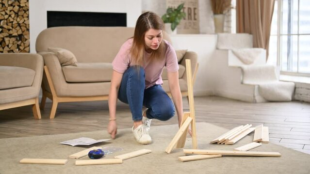 A young woman enthusiastically assembles a rack or shelf according to instructions that have errors