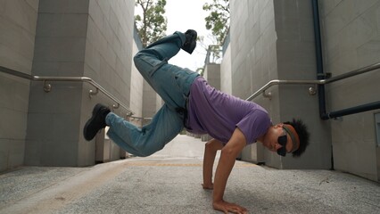 Professional break dancer perform street dance at narrow corridor. Skilled happy asian hipster moving to music while show b-boy step at narrow wall. Modern lifestyle. Outdoor sport 2024. Sprightly.
