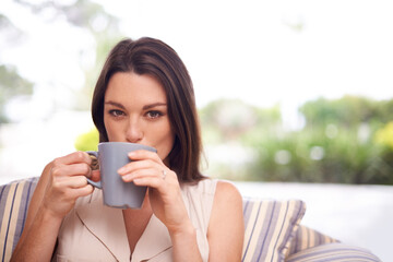 Woman, home and sofa with drinking coffee to relax or chill on break, day off and enjoy. Portrait, female person and happy in living room on couch with cup of tea for peace and calm in lounge.
