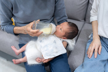 An 8-day-old Taiwanese baby who is held by his grandmother and drinks milk in a baby bottle...