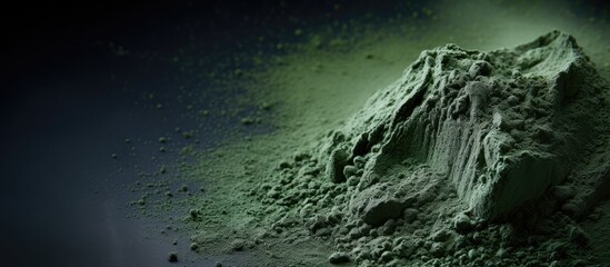 A mound of green powder contrasts against a dark background resembling the Earths horizon with clouds in the sky, creating an astronomical landscape