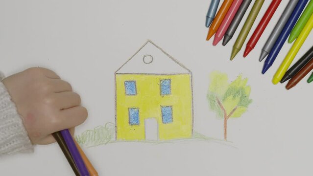 Close-up of hands of unidentified little child  drawing house .child coloring, colored pencils, preschool drawing