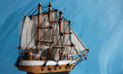 Rear view of a wooden model of a three-masted sailboat on a blue background
