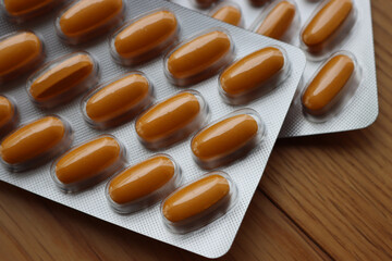 Pharmaceutical medicine capsules on wooden table. Orange pills in blister packaging