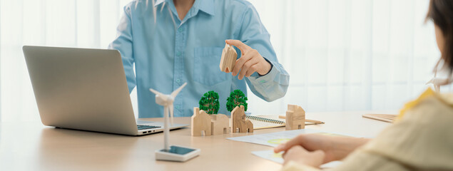 Two business people talking about eco city at green business meeting on meeting table with windmill...