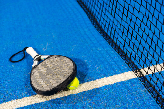 Paddle tennis racket, ball and net on the court