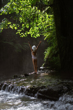 Woman traveler on an adventure at a tropical waterfall, Bali.