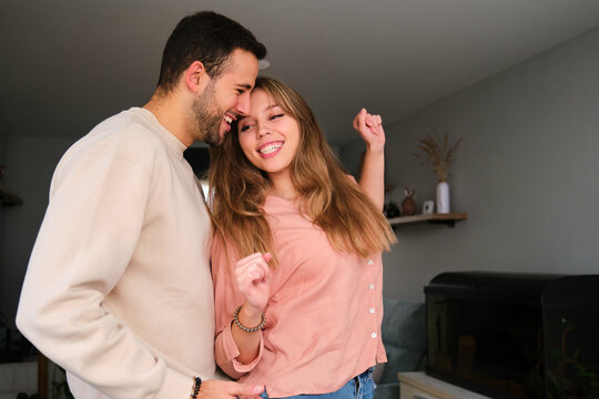 Spanish couple dancing and laughing together at home.