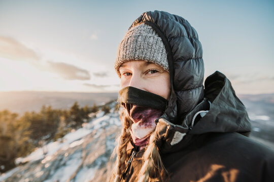 Young woman hiking in cold weather with neck warmer covering nose