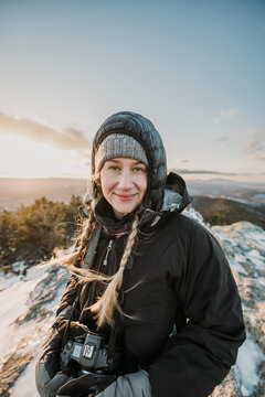 Portrait of young woman hiking in winter with camera around neck