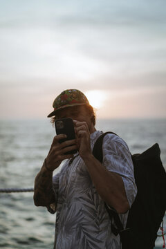Man traveler with backpack in tourist place takes pictures on phone.