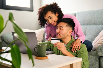 Multiracial happy couple shopping online, making a travel reservation.